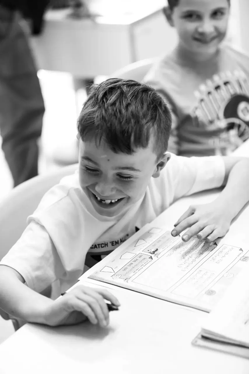 élève souriant à son bureau de classe. Ce moment capturé représente plus qu'un simple instant scolaire : c'est un fragment de ces années précieuses où l'enfant construit ses premières bases, où chaque nouvelle connaissance est une aventure, chaque découverte une source d'émerveillement. Elémentaire à l'école Galilée de saint Maximin.