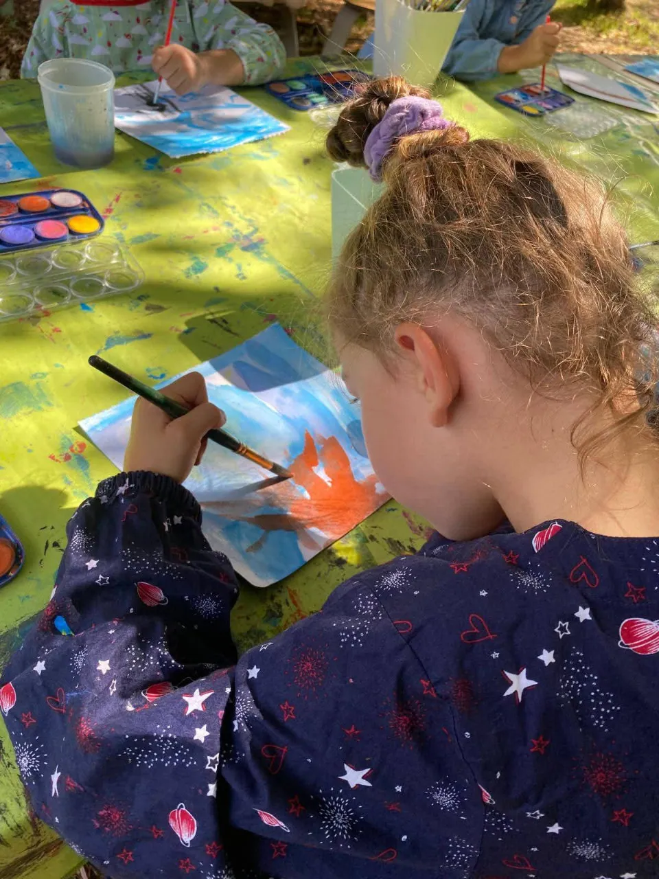 Sur cette photo les enfants sont sur un ateliers peinture en extérieur.